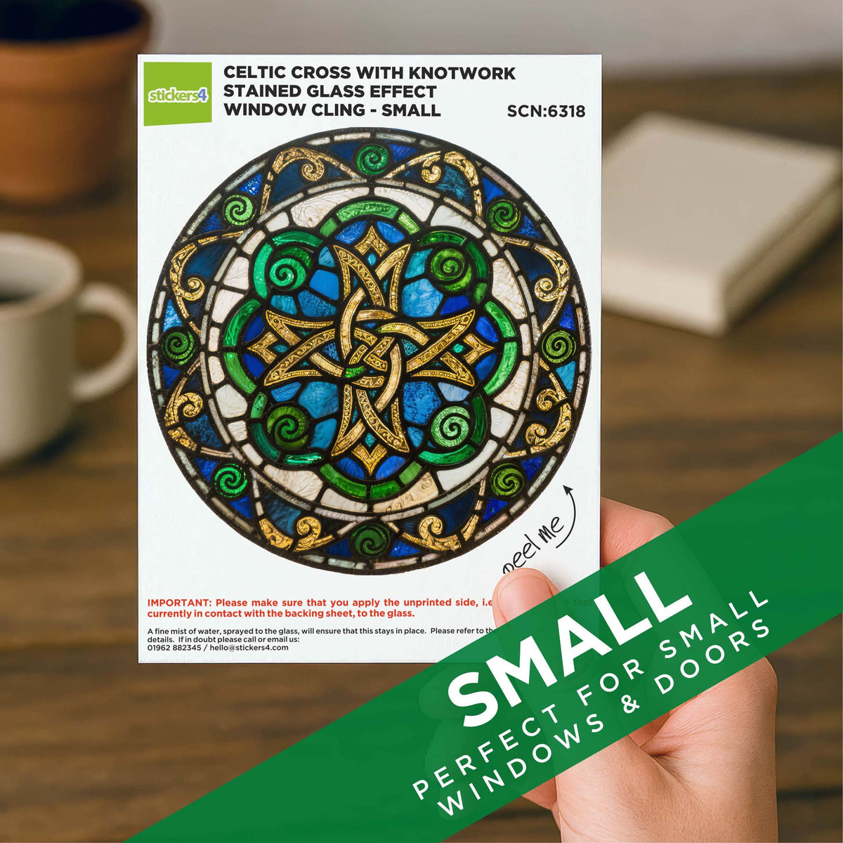 Window cling with Celtic cross design on a white card, held by a hand.