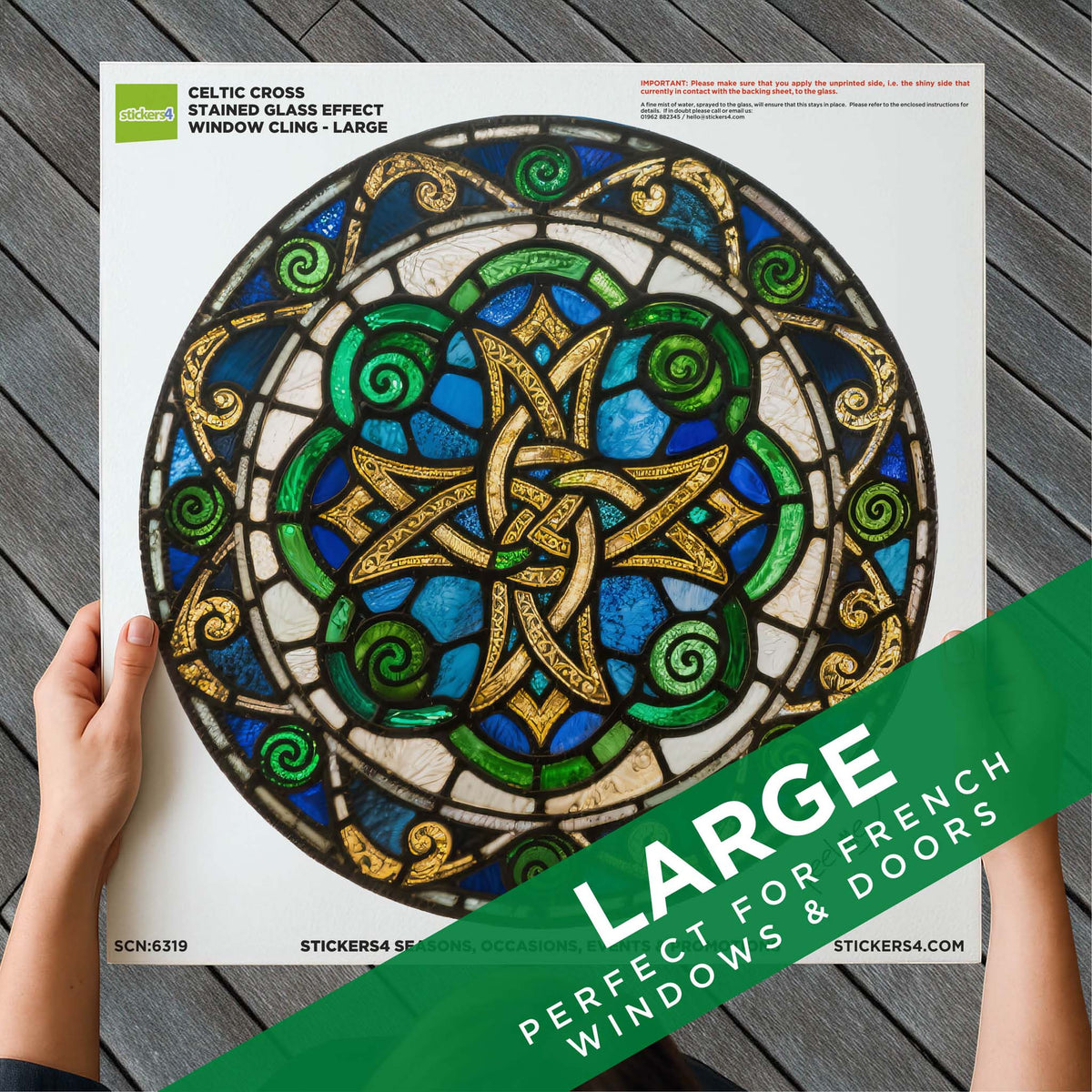 Stained glass effect window cling with Celtic cross design on a white backing, held by a hand.