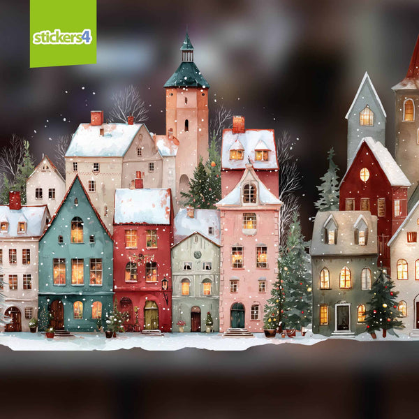 A decorative miniature village of colourful houses with snowy roofs and lit windows, shown as a product graphic with a blurred warm-toned background.  AVAILABLE IN TWO SIZES FOR SMALL & LARGE WINDOWS'.