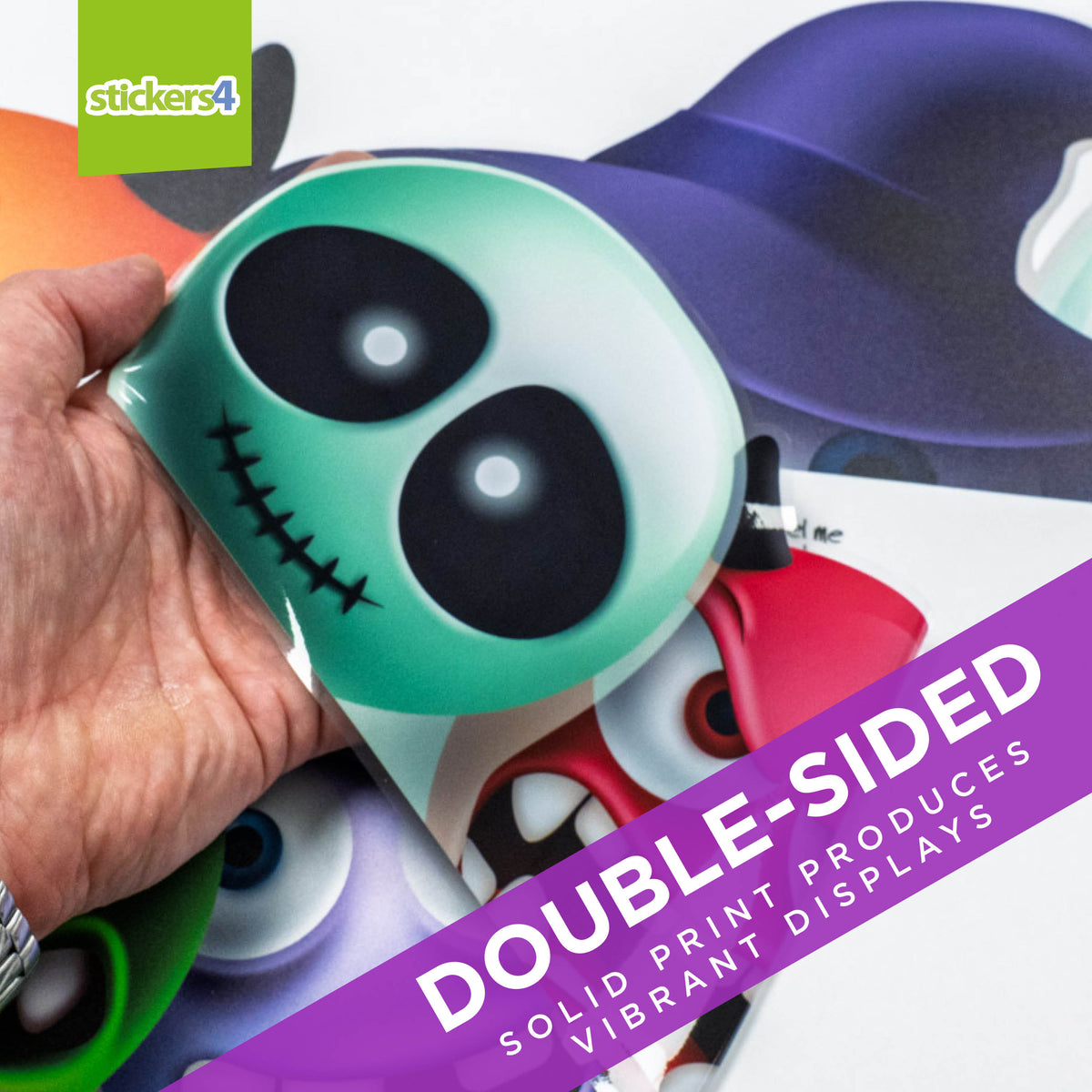 Hand holding a double-sided sticker with cartoon character design, featuring the brand &#39;stickers4&#39;.
