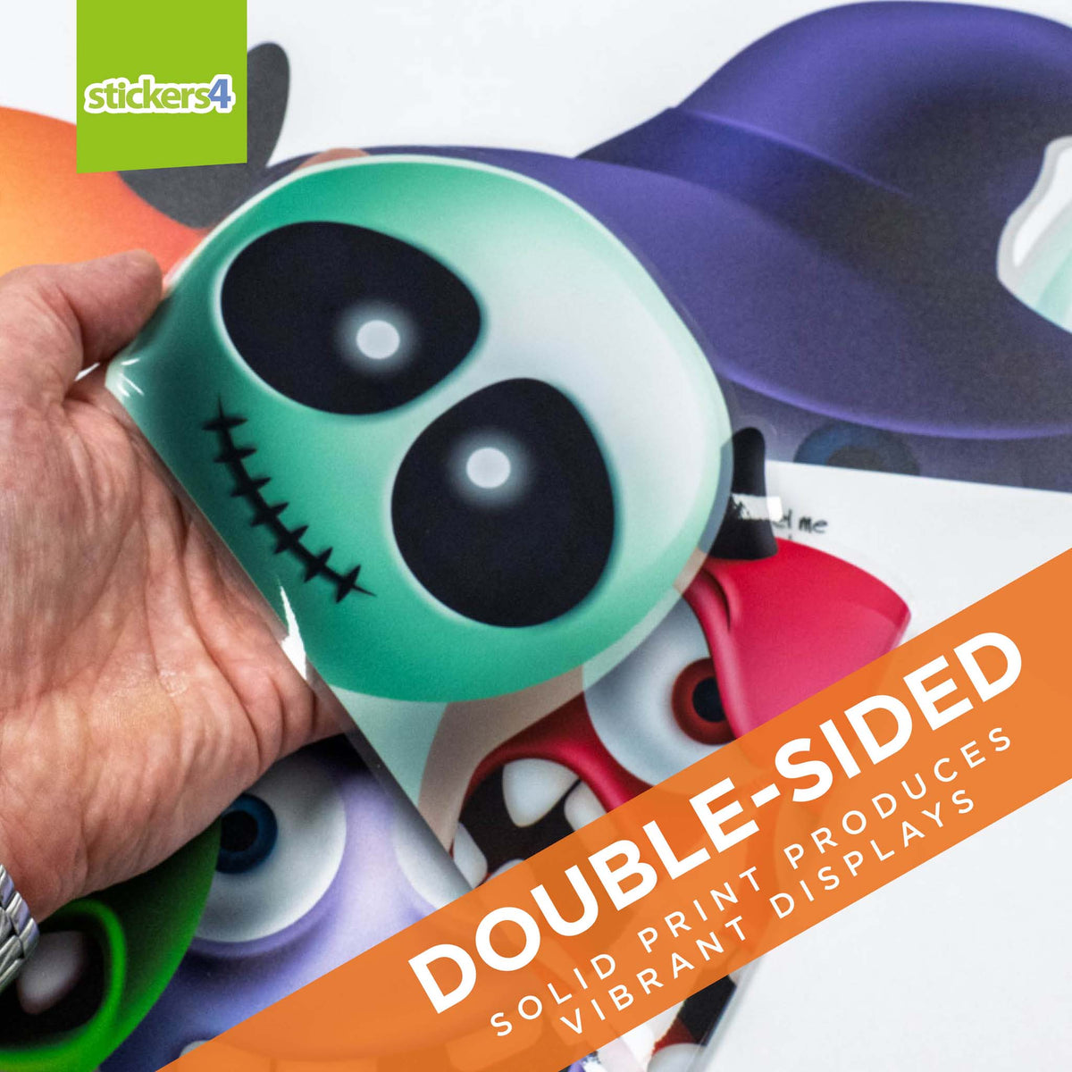 Hand holding a double-sided sticker with cartoon face design, colorful background with &#39;stickers4&#39; branding.